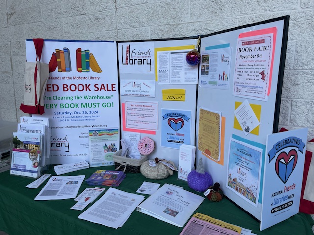 A tabletop trifold displays signs about upcoming events and offers newsletters and handouts to visitors.