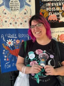 A smiling young woman shows her library card.