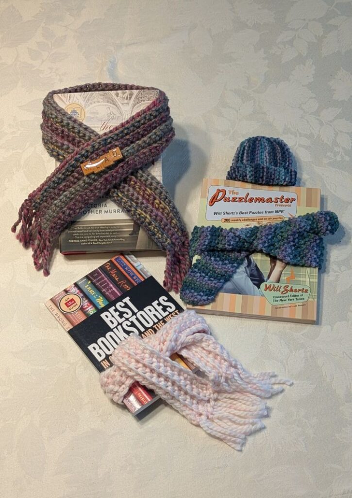 Small scarves are wrapped around books; a small hat sits atop one of the books.